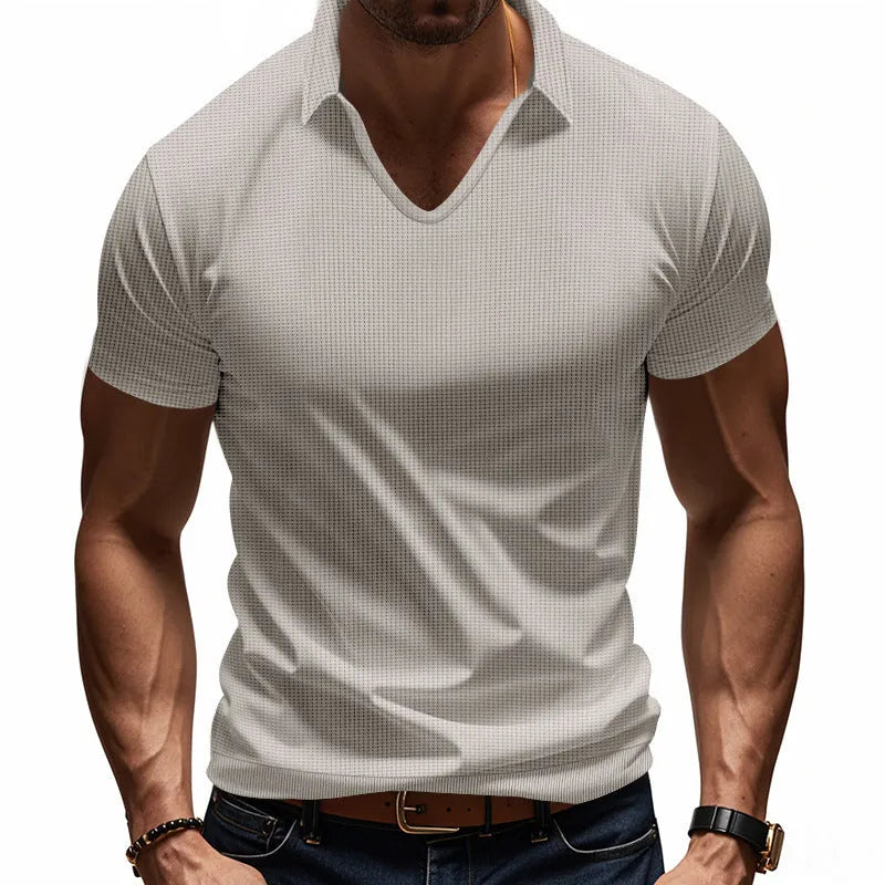 Man wearing a loose-fitting apricot V-neck short sleeve t-shirt against a plain background.
