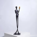Black cast aluminium sculpture of a woman reading, 51cm tall on a desk.