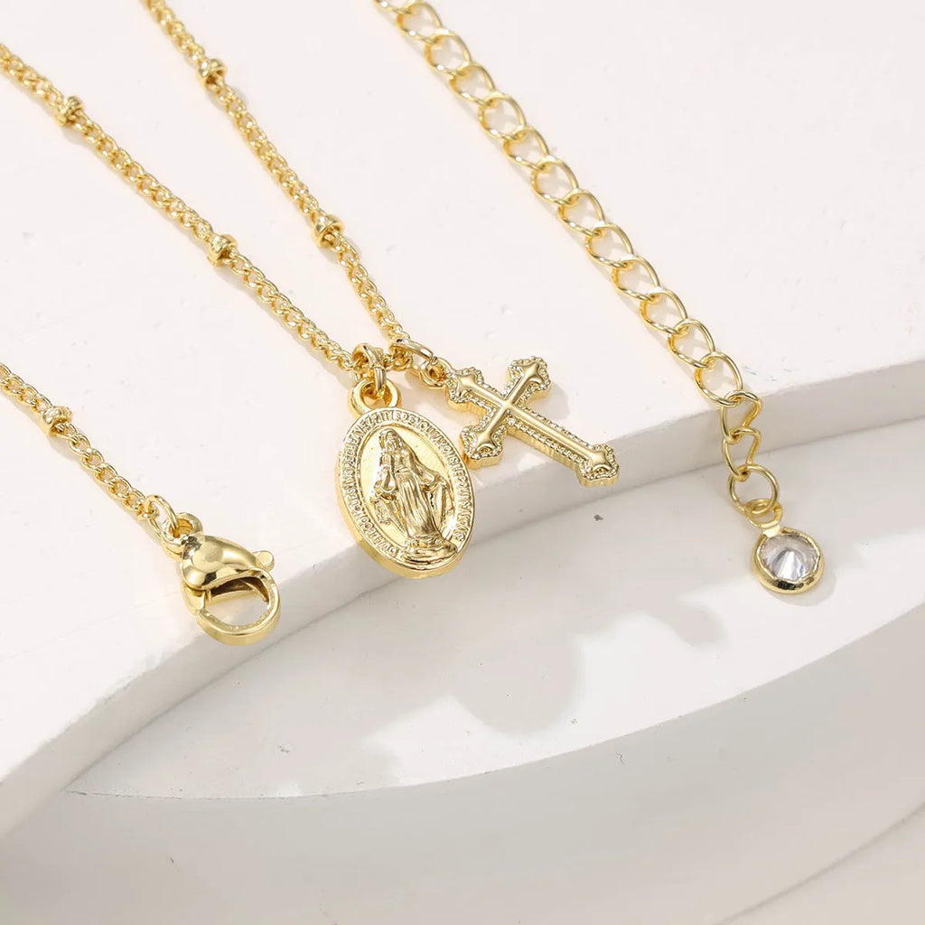 Gold-coloured Virgin Mary and cross pendant necklace on a chain.