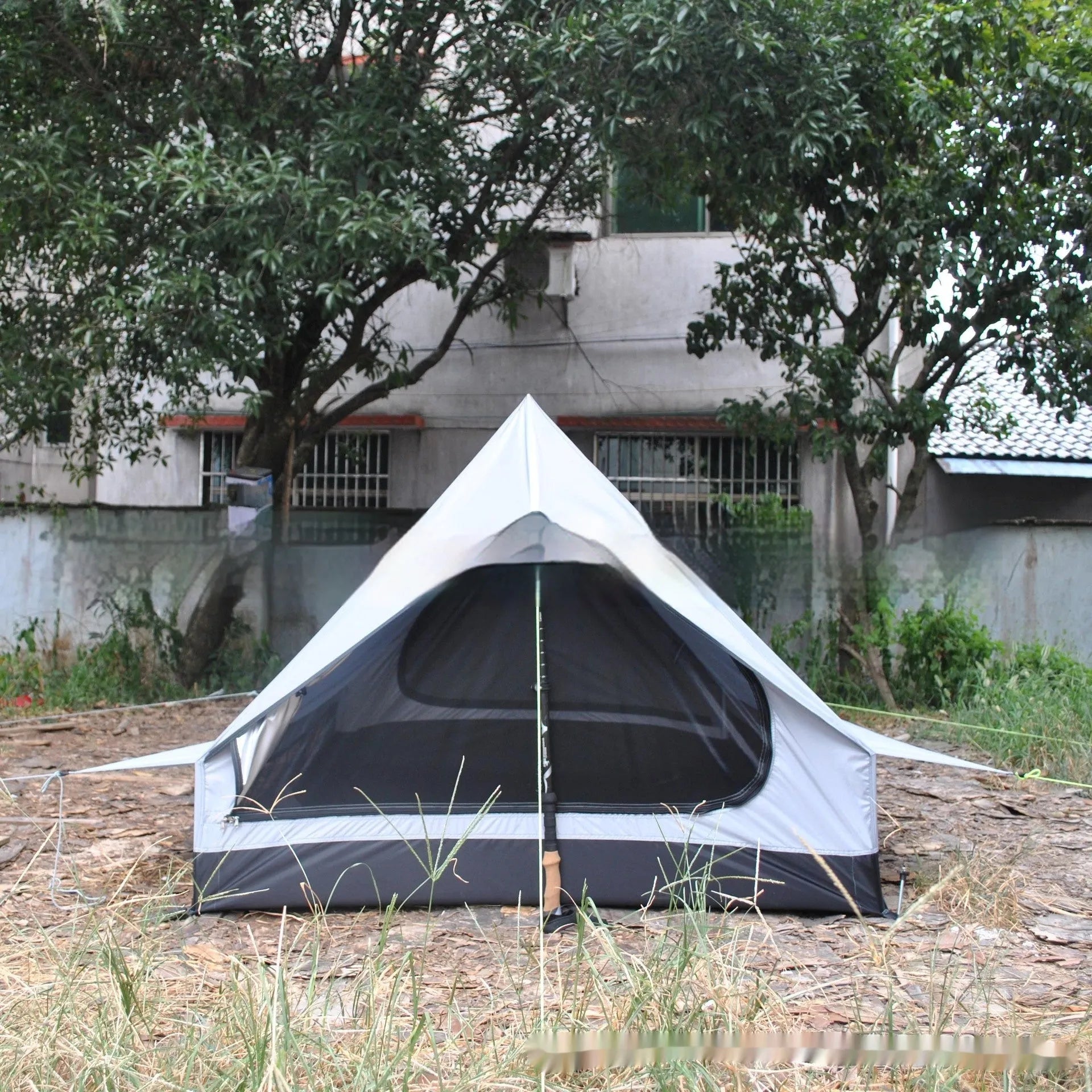 Brown A-frame hiking tent supported by hiking poles showing spacious interior for 2-3 campers