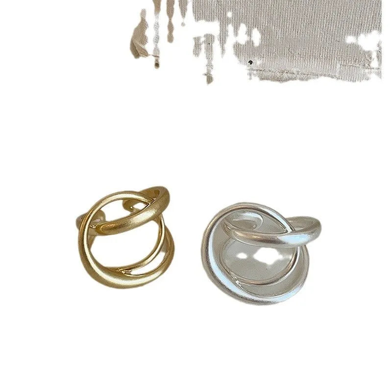 Geometric open ring for women with three-dimensional interlaced matte metal design in gold or silver.