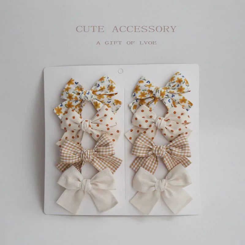 Children's fabric dovetail bow hairclips in eight colour sets including beige, blue flowers, coffee polka dot, green dots, pink, rice coffee, wine red plaid floral, and yellow