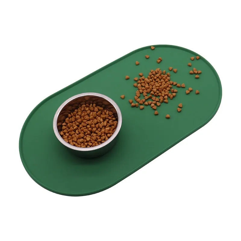 Green silicone waterproof placemat for cat bowls on a wooden floor.