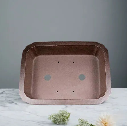 Antique rectangular purple clay flowerpot on a wooden surface with green boxwood plant inside