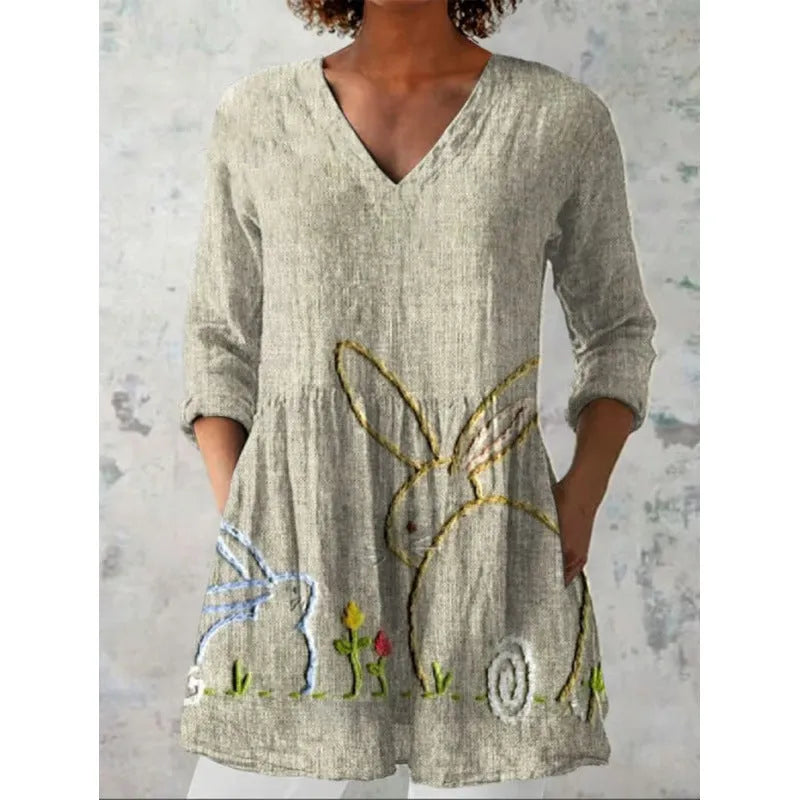 A woman wearing a vibrant printed loose-fitting dress with a wide waist and 3/4 length sleeves.