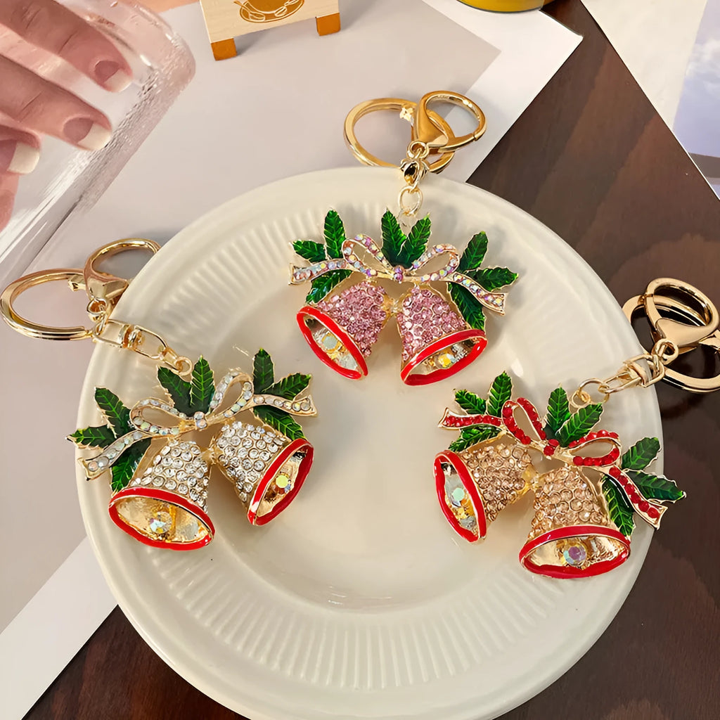 Christmas bell shaped metal keychain with diamond studded surface in champagne colour on white background