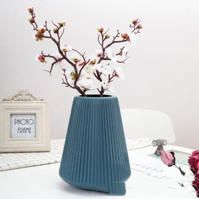Melamine plastic decorative vase in blue colour on desktop with floral arrangement