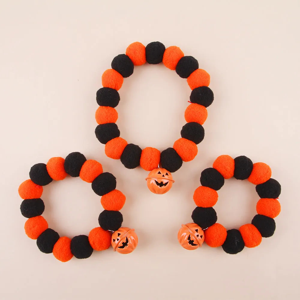 Orange Halloween pumpkin dog cat collar with green ribbon leaf, black stripes, jingle bell, and breakaway buckle on grey background.