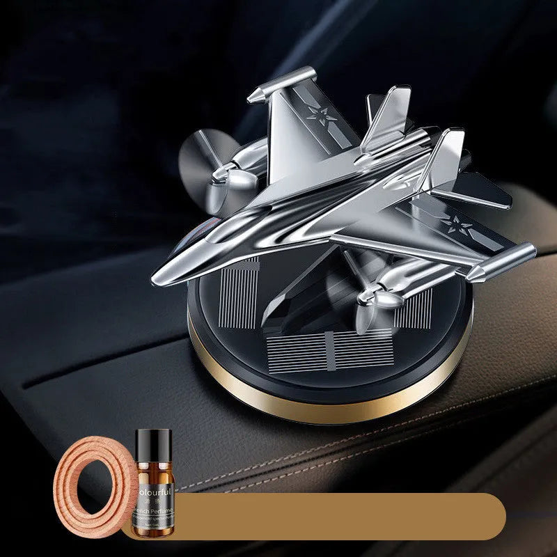 Solar powered rotating silver fighter aircraft perfume diffuser ornament on a car dashboard.