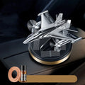 Solar powered rotating silver fighter aircraft perfume diffuser ornament on a car dashboard.