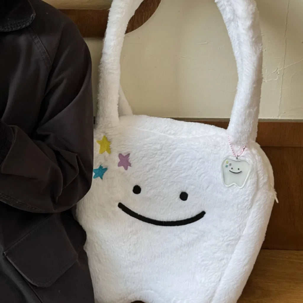White plush large tooth design shoulder tote bag with a zipper, shown as a unisex crossbody bag.
