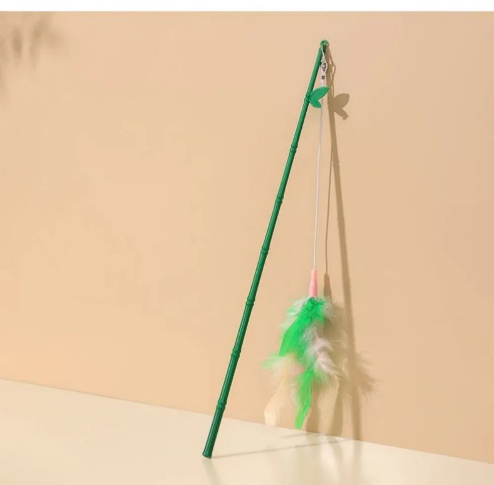 Green interactive cat feather wand toy with bells on a light background