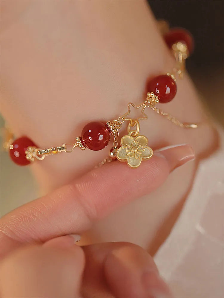 Red agate double layer bracelet with peach blossom charm on an adjustable elastic cord.