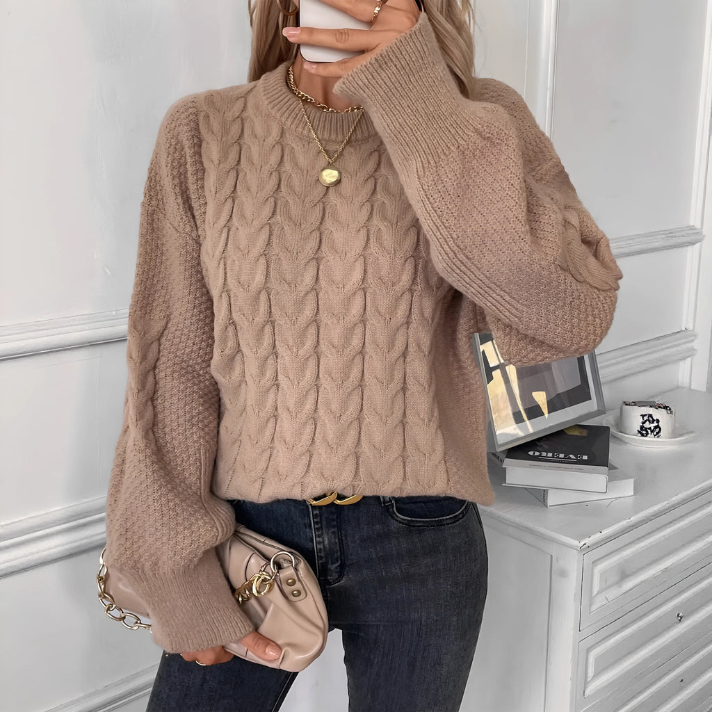 Women's loose beige pullover sweater with a twist detail and round neck on a hanger.