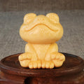 Solid bamboo smiling frog carving ornament with cartoon style on a wooden surface.