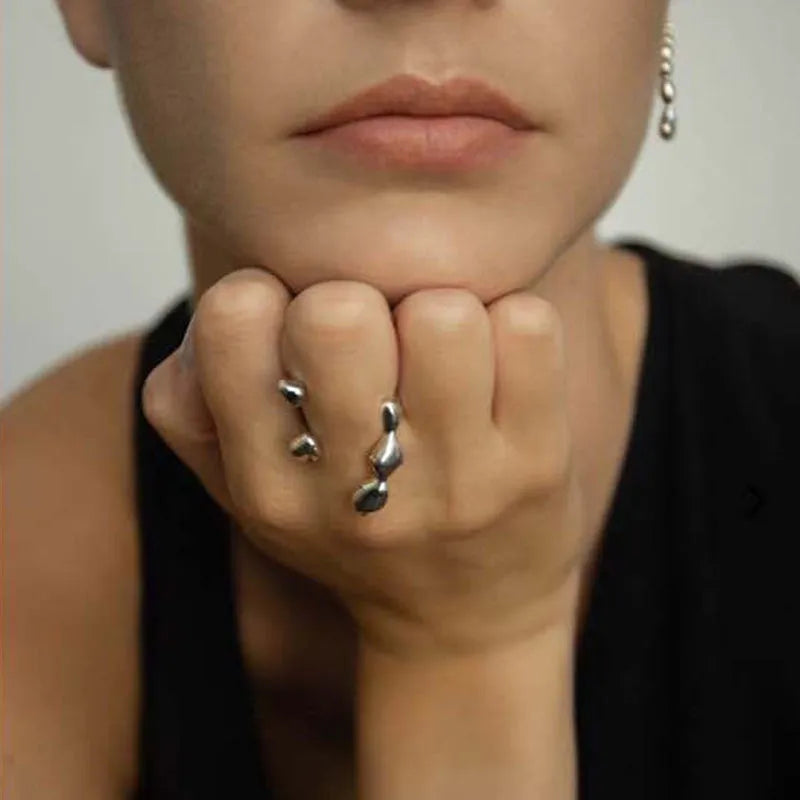 Brass opening ring with spherical element in gold colour on a hand.