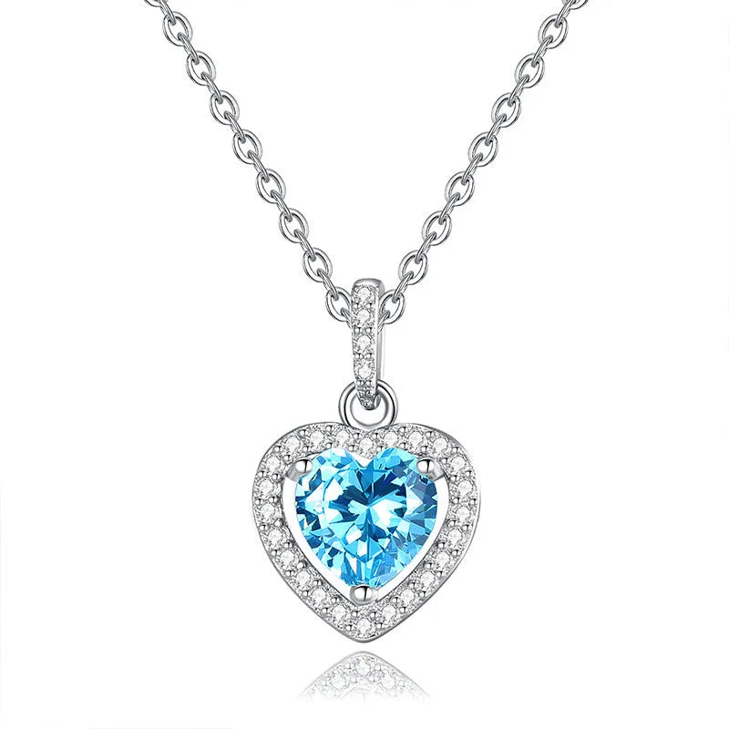 Sterling silver heart pendant necklace with inlaid gemstone on a cross chain, adjustable length.