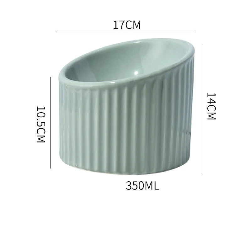 A dark green ceramic elevated cat bowl with a tilted, round rim on a wooden surface.