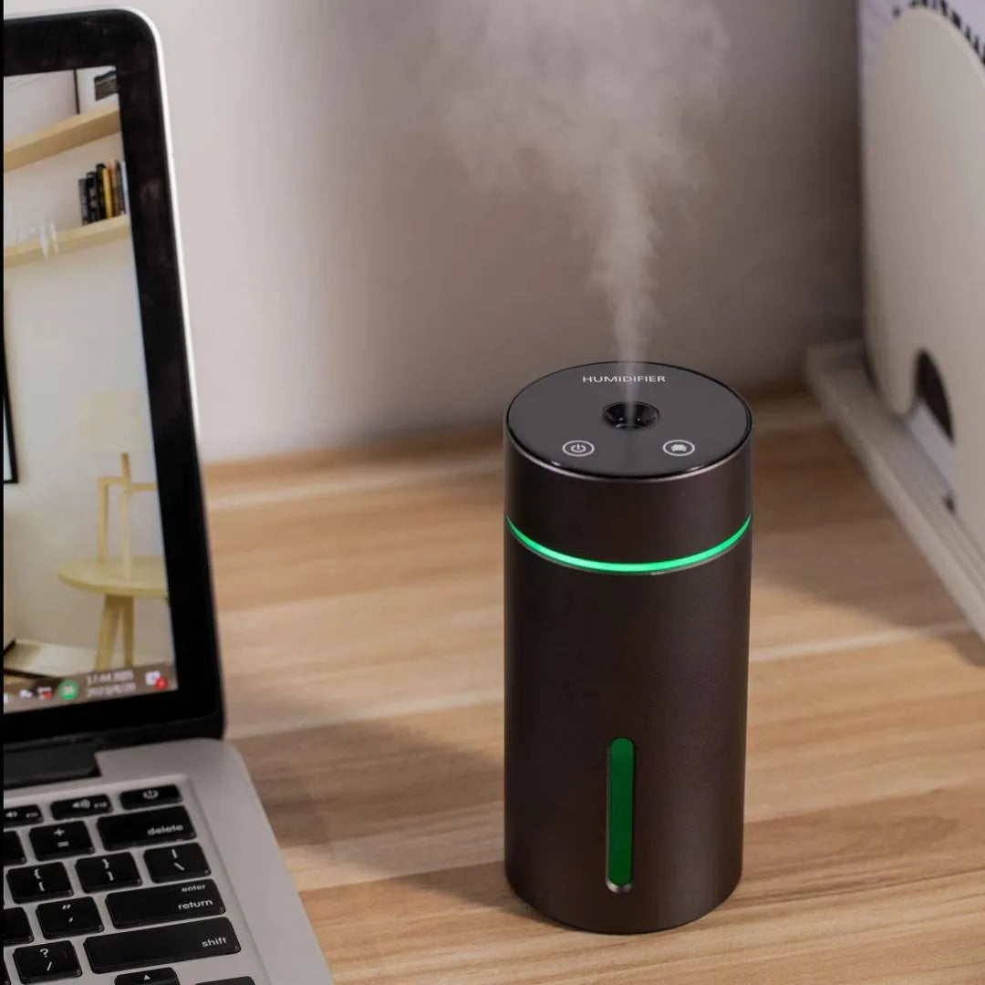 Black A6 aluminium alloy portable car humidifier and essential oil diffuser with USB cable on a desk.