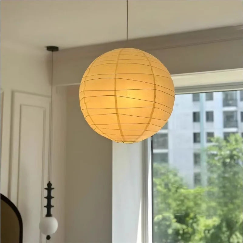 Japanese style rice paper pendant chandelier hanging from a ceiling, providing soft ambient light.