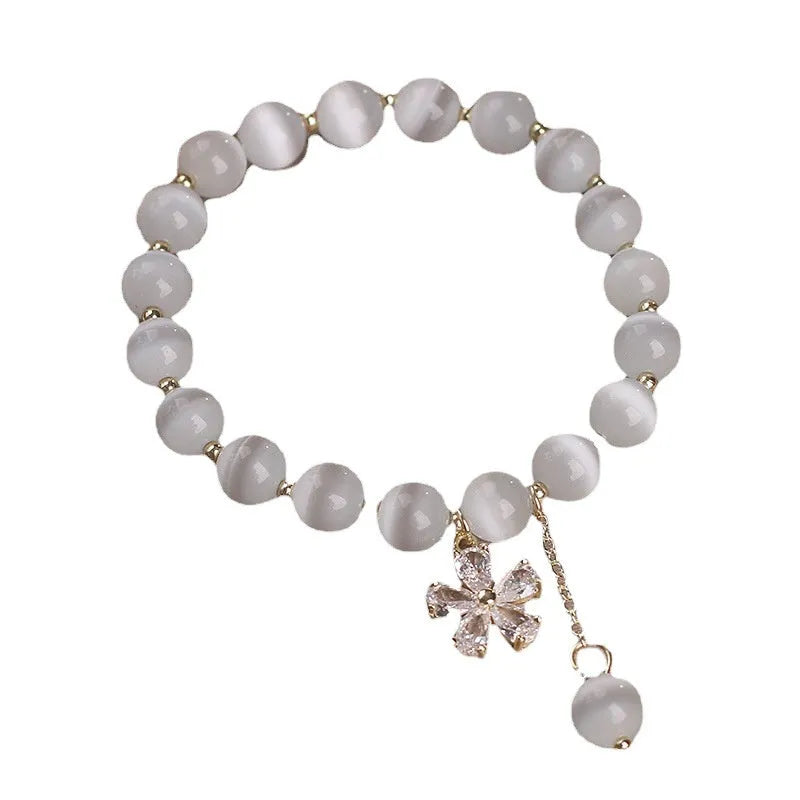 Women's white cat's eye crystal bracelet with flower decoration, tassel detail, and morganite safety buckle pendant