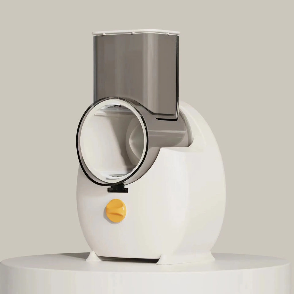 White electric vegetable slicer with rotary blades, suction base, and feeding port on a kitchen counter.