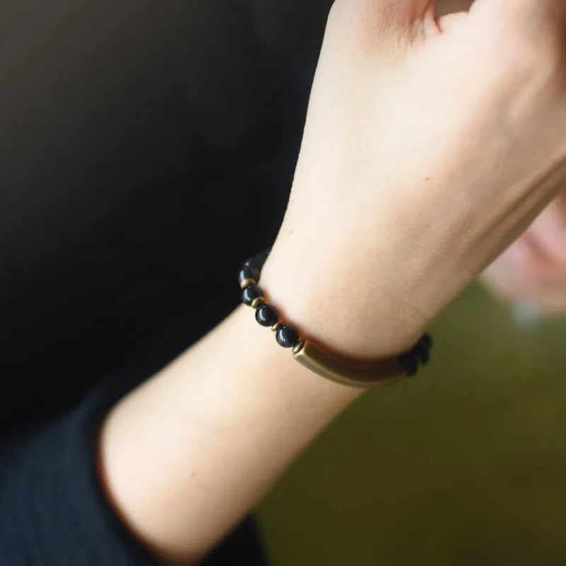 Layered retro ethnic bracelet with water plants agate, obsidian, and red stone beads and brass accents on a neutral background.