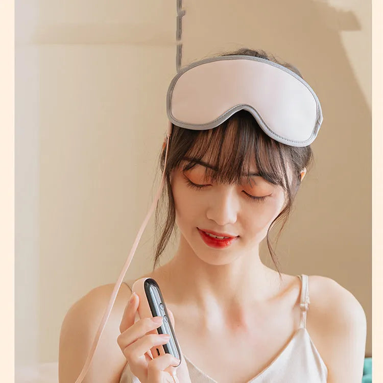 Pink and green portable USB-powered eye massage goggles with a suede shell on a grey background.
