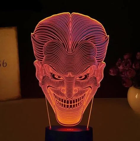 A 3D acrylic LED table lamp with a remote control on a desk, showing its colourful gradient light mode.