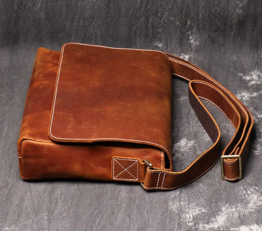 Vintage brown leather mens messenger bag with a shoulder strap, shown open to reveal internal organiser pockets.