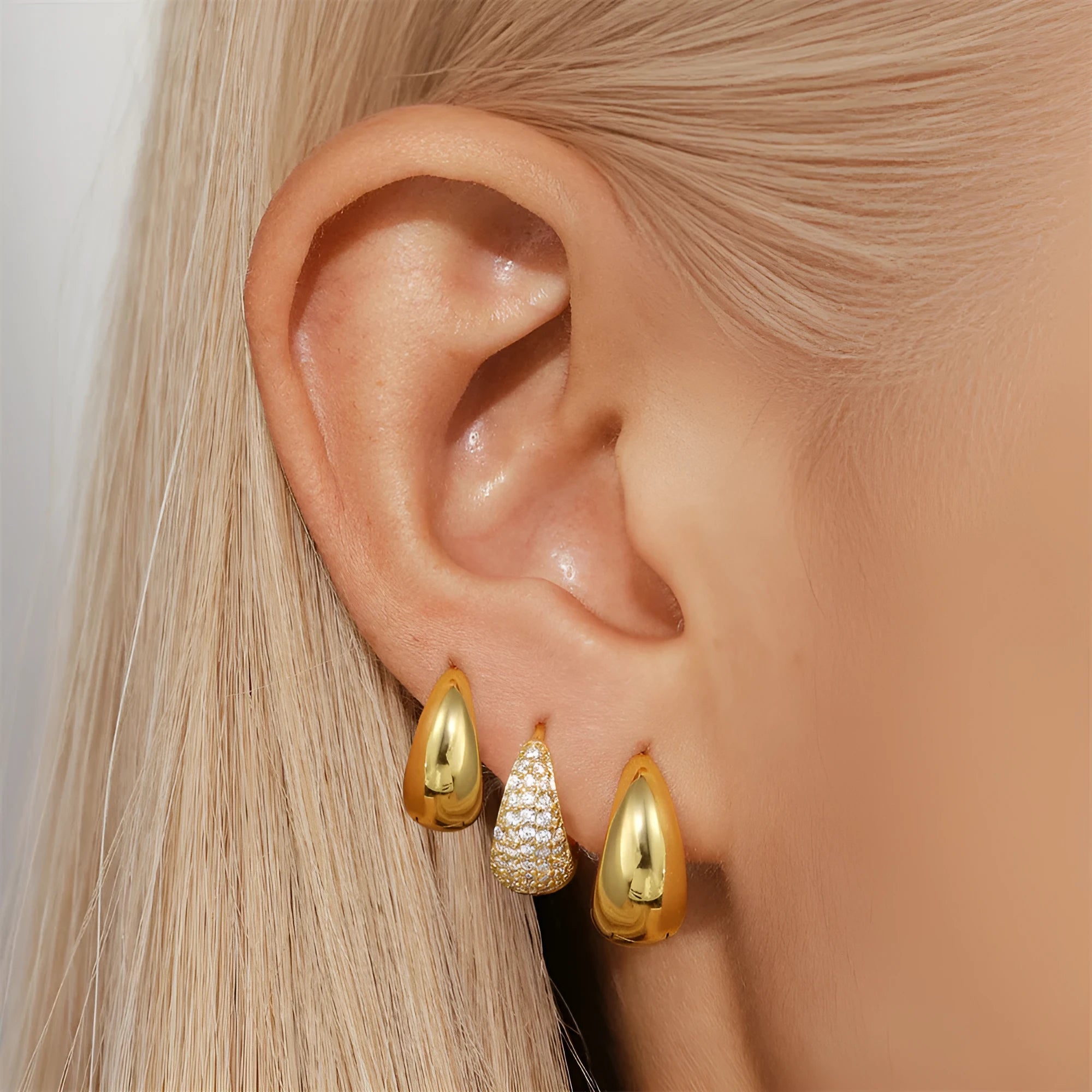 A pair of golden brass diamond-shaped earclip earrings with a round geometric design.