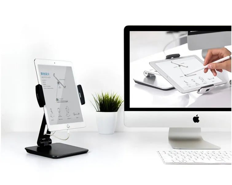 Folding aluminium and black plastic phone tablet stand on a desk, showing 360 degree rotation base.
