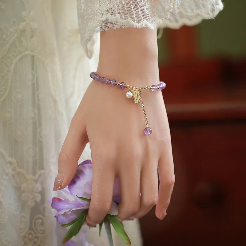 Natural crystal bracelet with romantic lavender amethyst beads, available in dark or light colour, on a plain background