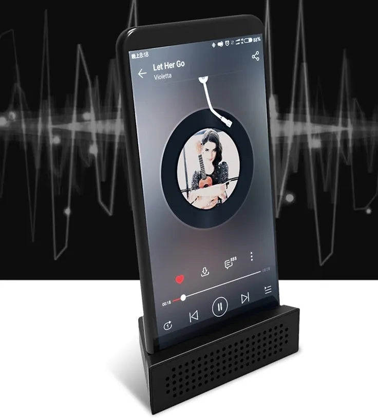 Portable black ABS plastic phone amplifier holder with an iPhone inserted, shown on a desktop.