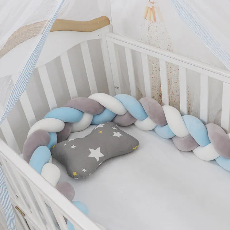 Braided knot crib bumper in spandex velvet wrapped around a white cot for infant safety protection.