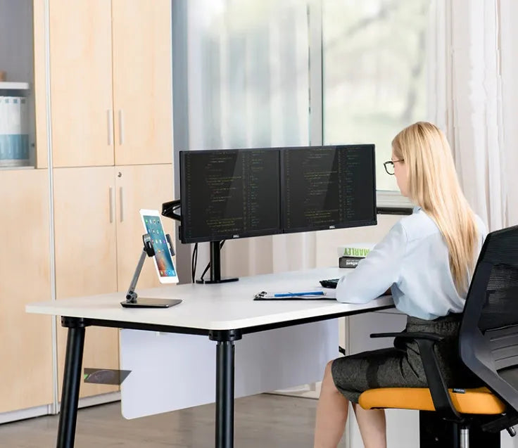 Folding aluminium and black plastic phone tablet stand on a desk, showing 360 degree rotation base.
