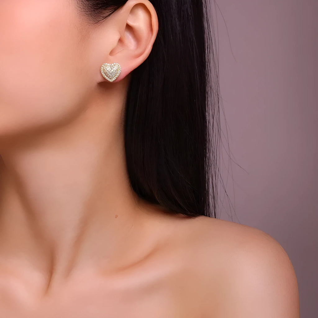A pair of simple S925 sterling silver stud earrings with a gold-coloured finish and a heart-shaped moissanite stone.