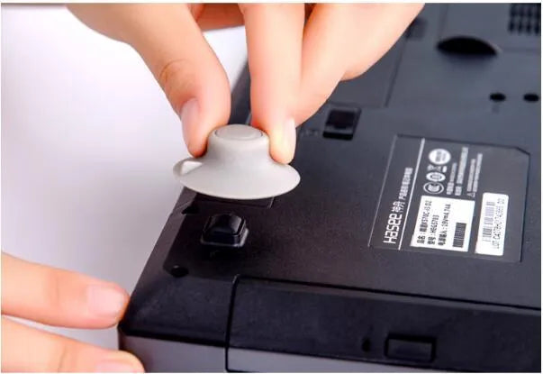 Grey durable plastic laptop cooling pads, two large and two small, on a desk next to a notebook