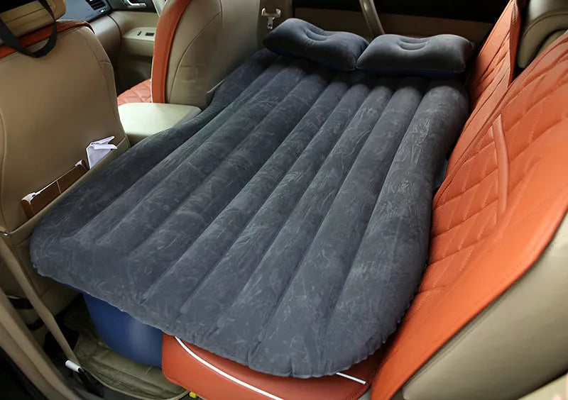 Black inflatable car bed with pillows, set up in the back of a five-seater car.