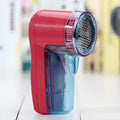 Portable electric clothing lint remover showing compact white body and shaving head