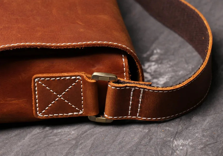 Vintage brown leather mens messenger bag with a shoulder strap, shown open to reveal internal organiser pockets.