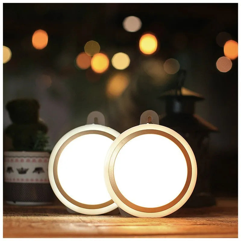 Round white motion sensor LED light unit with battery compartment, 80mm diameter.