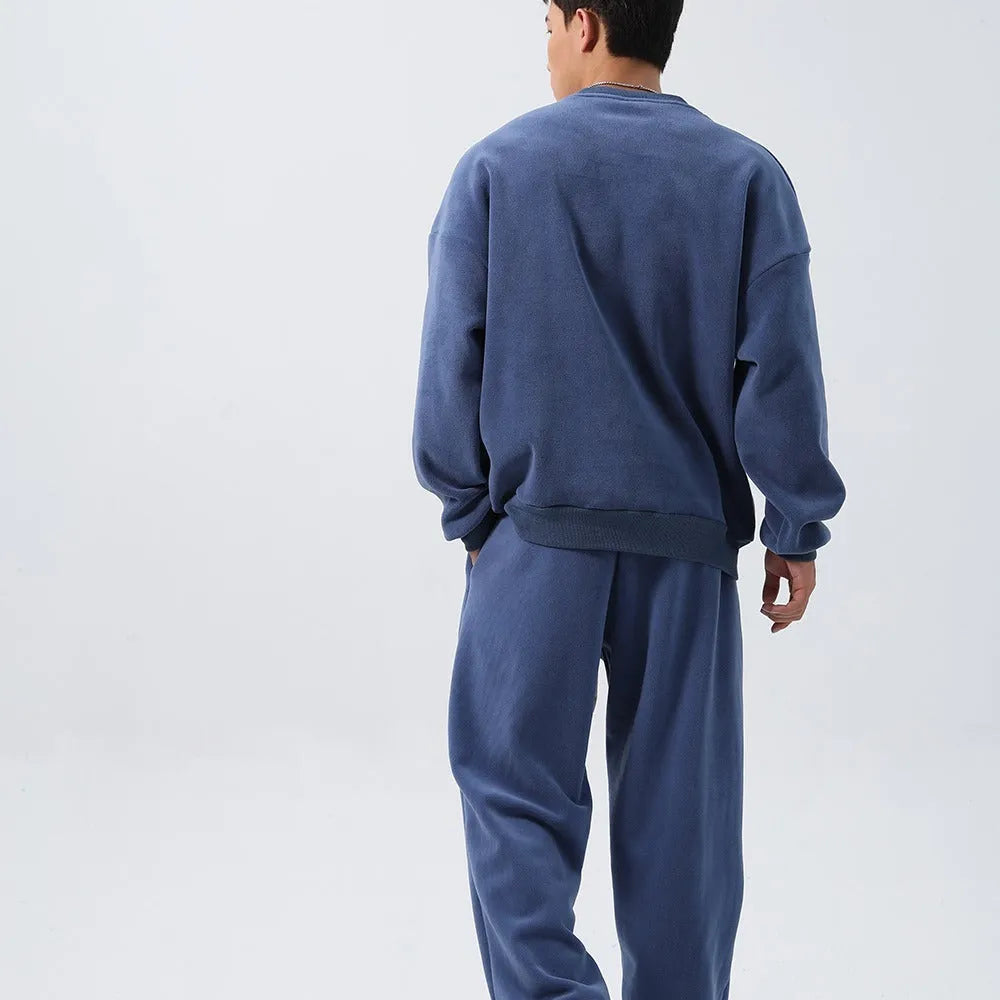 Man wearing a black loose-fit polar fleece sports suit with crew neck top and padded trousers for winter.