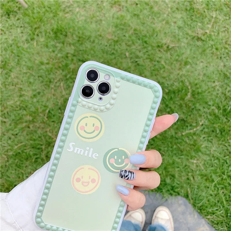 Green flexible TPU iPhone case with geometric smiley face and polka dot frame design.