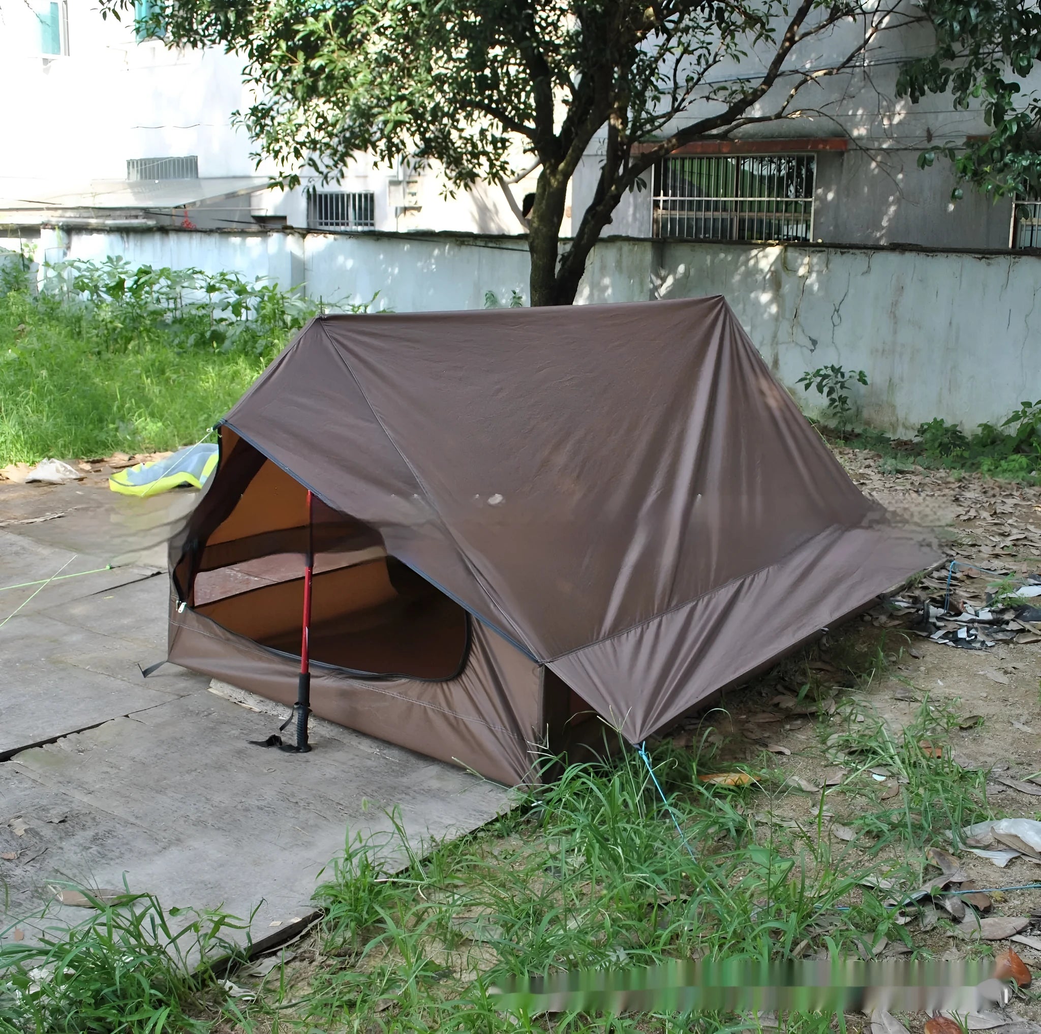 Brown A-frame hiking tent supported by hiking poles showing spacious interior for 2-3 campers