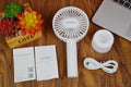 White ORICO FH1 handheld USB rechargeable small fan with three-speed buttons on a desktop.