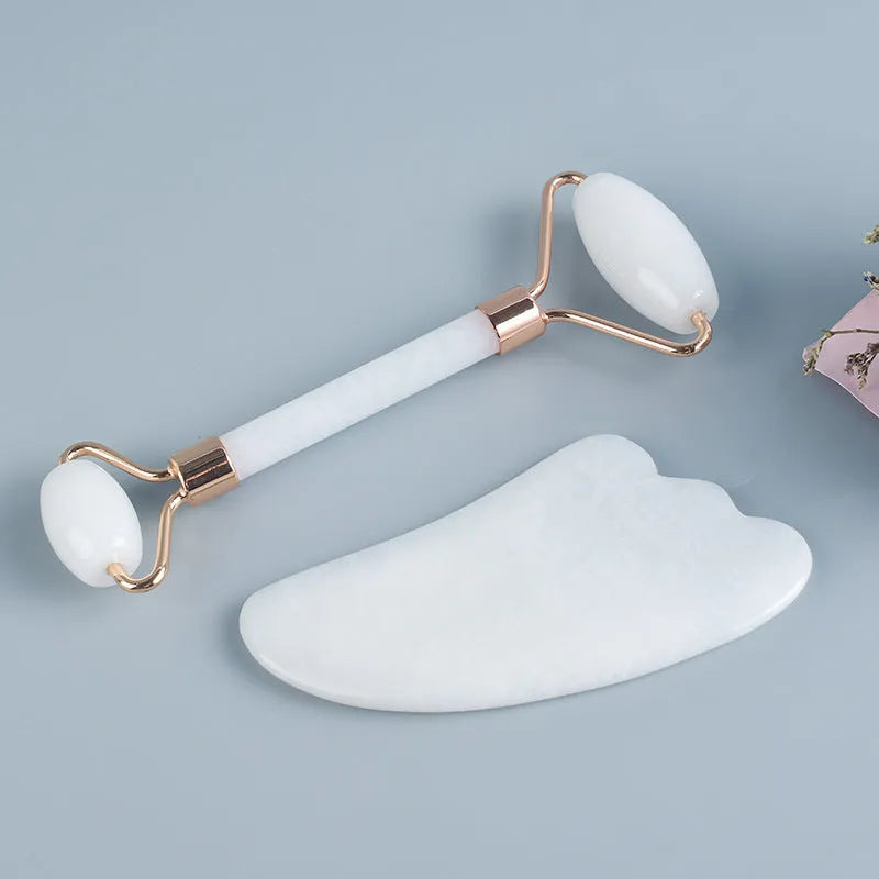 White jade double-headed facial roller and gua sha scraping board set on a storage tray.