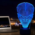 A 3D acrylic LED table lamp with a remote control on a desk, showing its colourful gradient light mode.