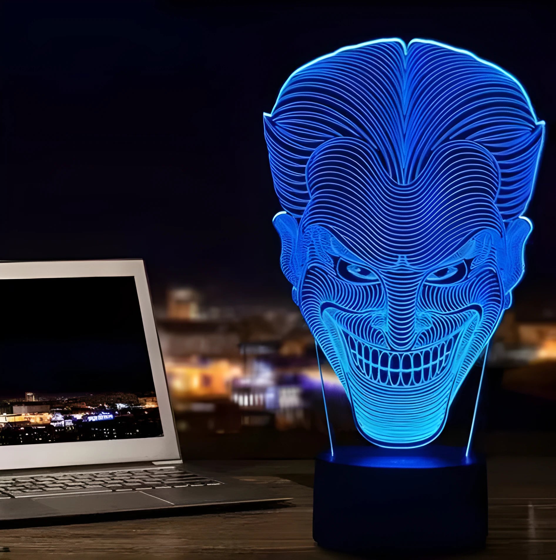 A 3D acrylic LED table lamp with a remote control on a desk, showing its colourful gradient light mode.