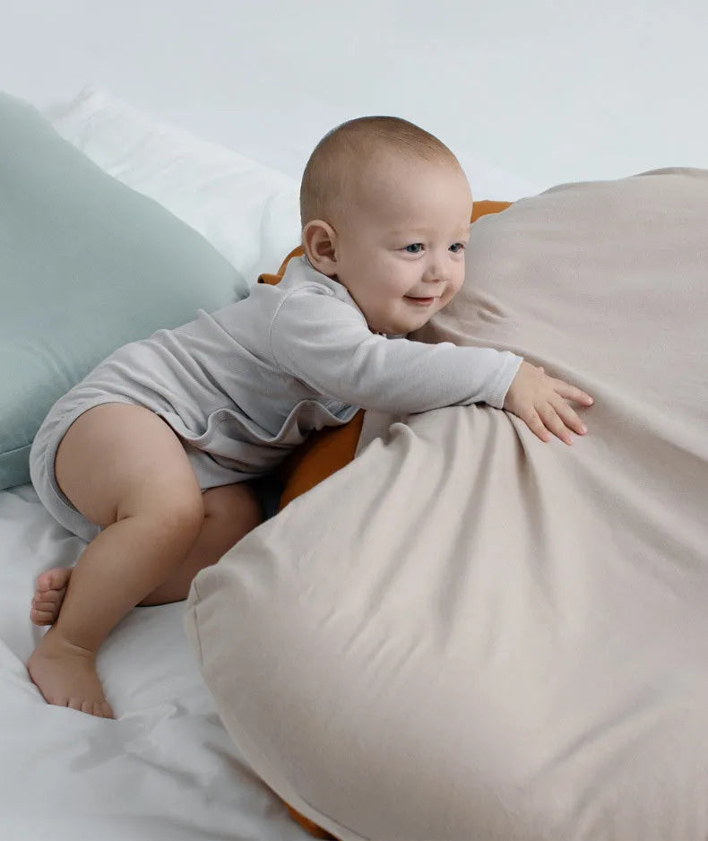 Beige portable baby nest cot cushion measuring 75cm by 45cm on a floor.